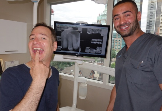 Patient points to tooth implant beside Dr Kadivi