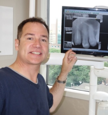 patient poses beside Xray of work to be done