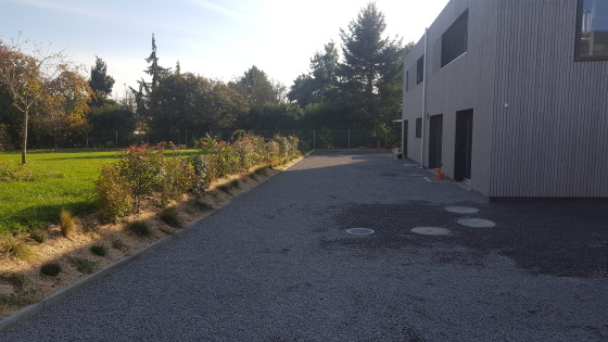 Cour en gravier et haie fleurie à Ecublens.