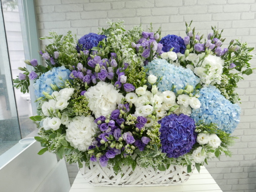 BK565 {As shown size}  -  A whirlwind of flowers appear to emerge from the seemingly disordered basket weaves. The nebula of flowers comprises Hydrangeas, Eustomas, Matthiolas and Waxflowers, creating a wonderful pattern of colours and textures.