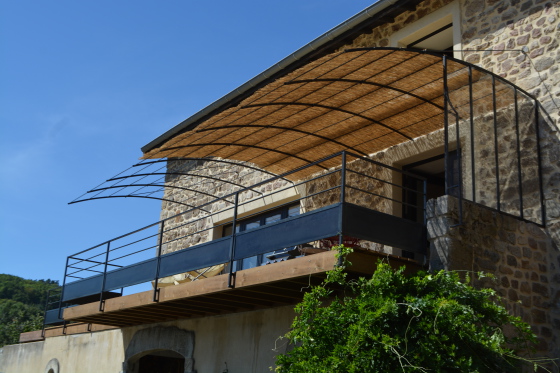 Agencement extérieur avec garde-corps , tonnelle suspendu et petite verrière coupe vent pour une terrasse tout confort .