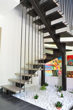 Escalier deux-quarts tournant sur limon centrale avec garde-corps intégré au platine, sans soudure apparente, patiné à la cire. Les marches sont en béton effet ciré