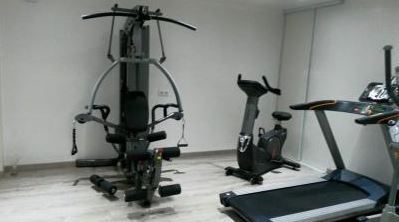 Salle de sport avec elliptique, vélo, tapis de cours, rameur, complet de musculation, banc, haltères et petits matériels
