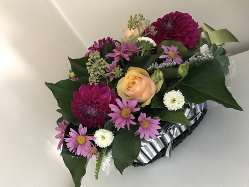 Compact arrangement in a basket with dahlia, roses, chrys, aster, ivy berry, succulents and ivy foliage