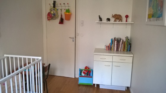 Tout est rangé à sa place. Les livres sont accessibles pour un jeune enfant, non loin du bureau. Les jouets sont soit présentés joliment, soit rangés hors de vue dans le placard blanc qui se fond dans le décor.