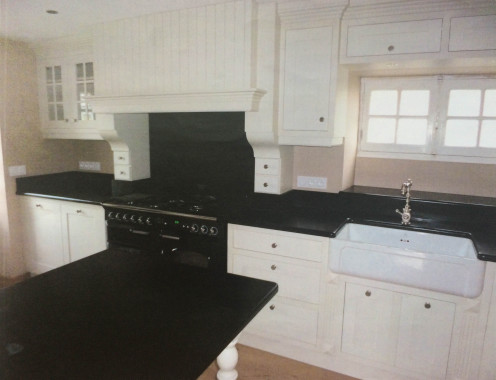 Cuisine sur-mesure réalisée dans un esprit maison de campagne. Chêne laqué et plan de travail en pierre noire. 
Surface : 11 m²
